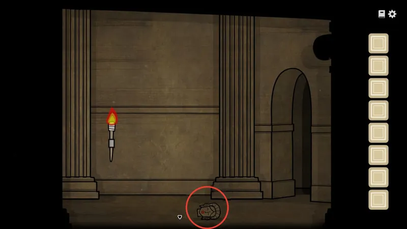 Lit torch on the wall with the statue head circled on the floor
